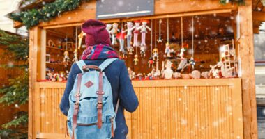 Woman tourist with backpack chooses holiday decor gifts at Christmas market Woman tourist with backpack chooses holiday decor gifts at Christmas market