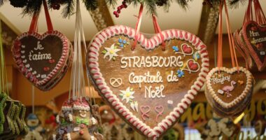 Gingerbread cookies in shape of hearts hanging from stall with messages of Christmas, Love and Strasbourg and a gingerbread man at the Strasbourg Christmas Market