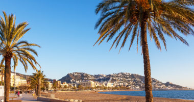 ROSES, GIRONA, SPAIN - JAN 22, 2012. Tourists strolling along the beach of Roses in winter. The friendly, sunny climate of the Costa Brava is one of the most attractive aspects of the region.