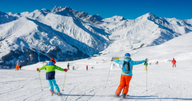 Back view of Cute happy skier boy with his mother having fun in a winter ski resort.