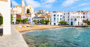 White houses and blue sea in Cadaques port with church and beach, Costa Brava, Spain