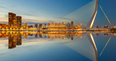 The Erasmusbrug and the Rotterdam skyline by night with a reflection in the water, a famous landmark in the Netherlands and travel destination - Travel image
