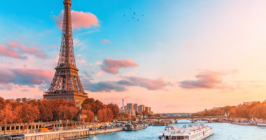 The main attraction of Paris and all of Europe is the Eiffel tower in the rays of the setting sun on the bank of Seine river with cruise tourist ships