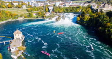 Rhine Falls (Rheinfall), Switzerland panoramic aerial view. Tourists boats in waterfall. Cliff-top Schloss Laufen castle, Laufen-Uhwiesen. View of Neuhausen am Rheinfall town in the background