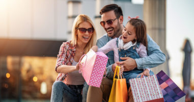 Happy family with shopping bags.Family shopping.Young parents and their daughter are carrying shopping bags.Happy family with shopping bags resting after shopping.