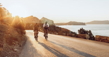 Two professional male cyclists riding their racing bicycles in the morning together on coastal road
