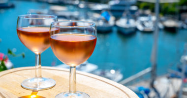 Tasting of local cold rose wine in summer with sail boats haven of Port grimaud on background, Provence, Var, France