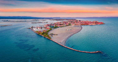 Beautiful summer scenery. Breathtaking summer view  from flying drone of public beach of Grado port, small town located between Venice and Trieste. Magnificent evening seascape of Adriatic sea.