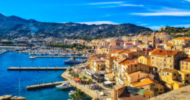 Corse Calvi historic city center with sandy beach, historic houses and harbor with boats and yachts, Corsica, France, Europe.