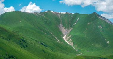 A beautiful view of the Caucasus Mountains in summer in the Gudauri region. The snow melts and a mountain river is born.